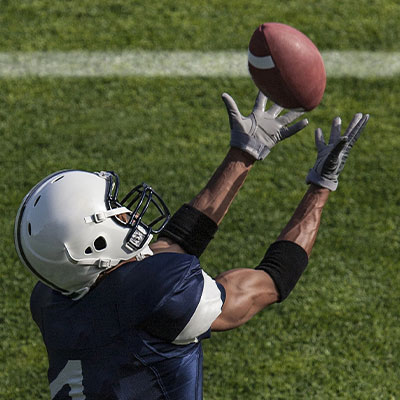 Player catching the ball wearing American Football Gloves